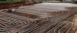 Hydronic underfloor heating pipes laid out on steel reinforcement mesh during a concrete slab installation